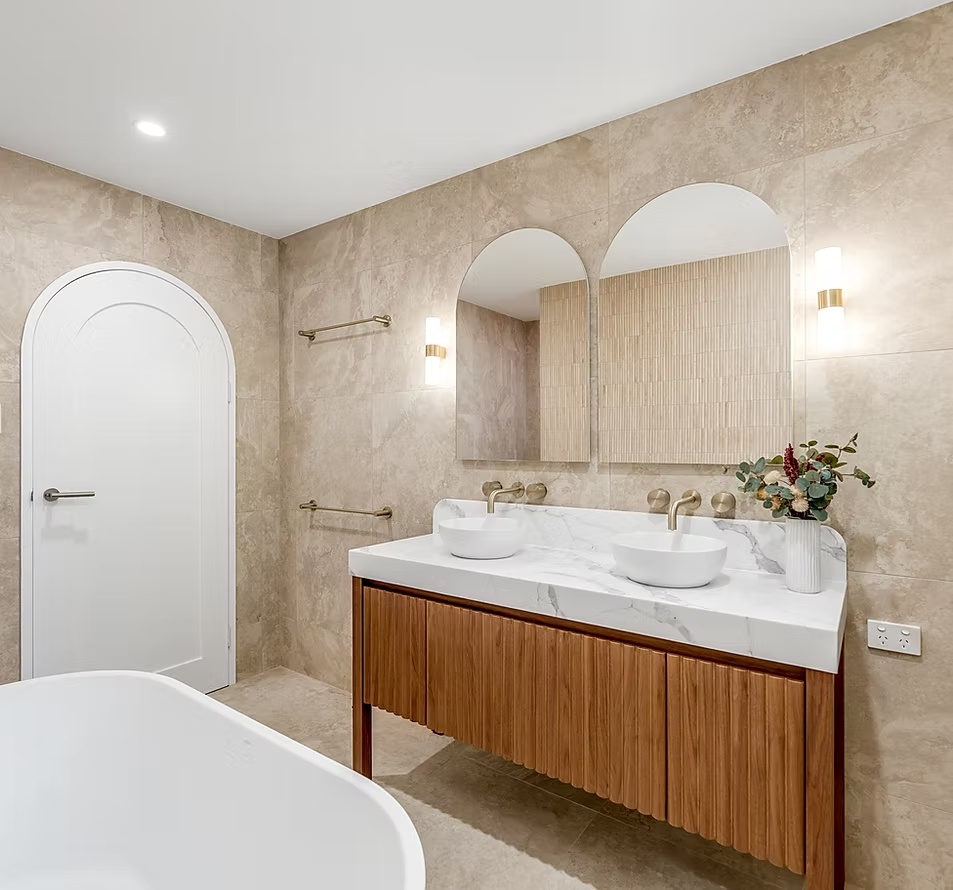 Bathroom vanity with arched mirrors and detailed wall tiling