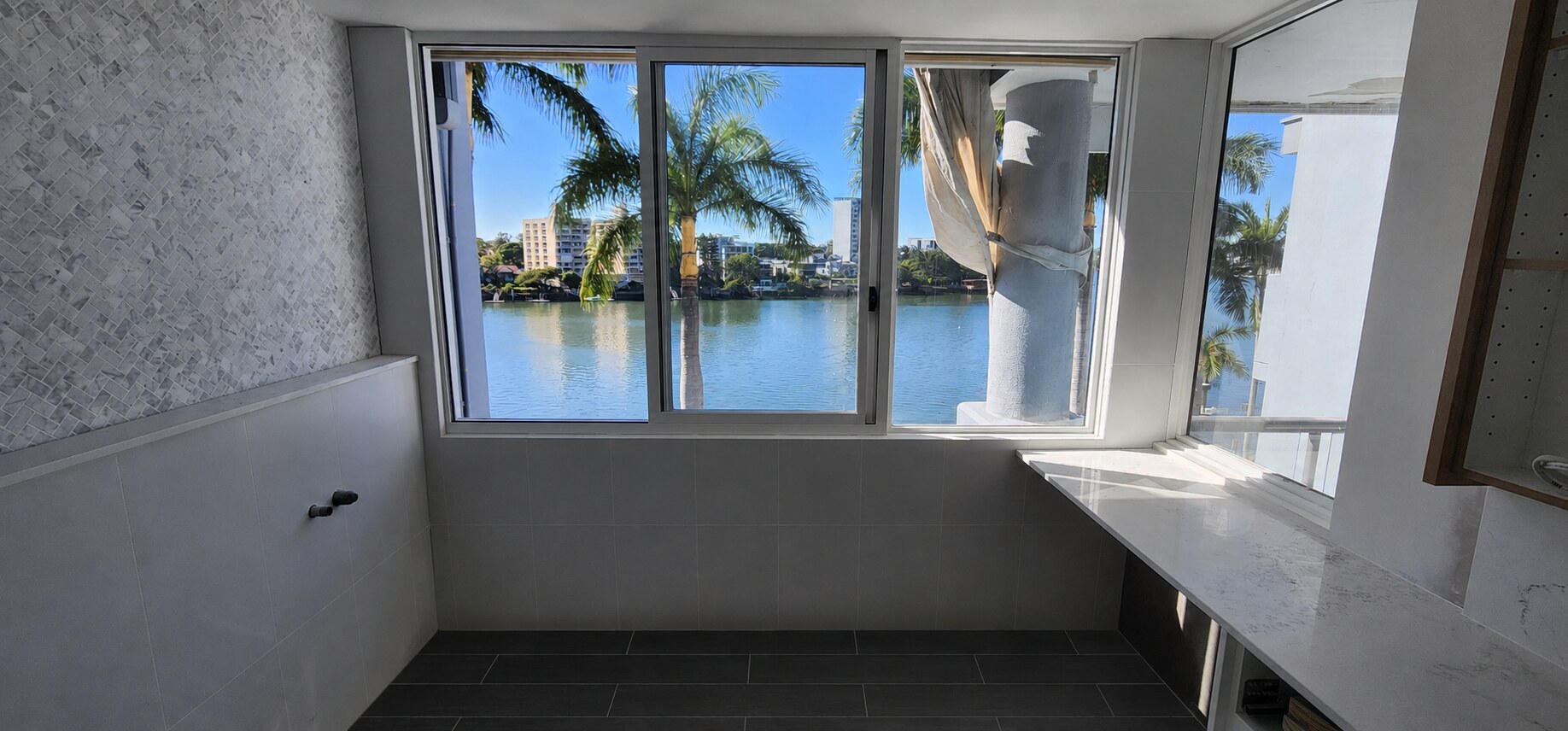 Brisbane waterfront bathroom with black floor tiles and mosaic feature wall